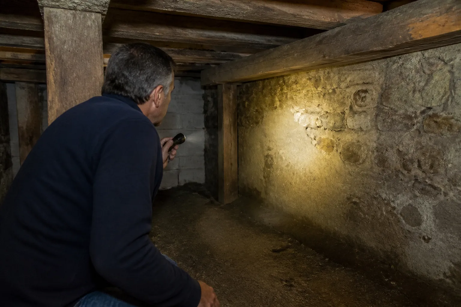 Expert inspectant un sous sol avec une lampe