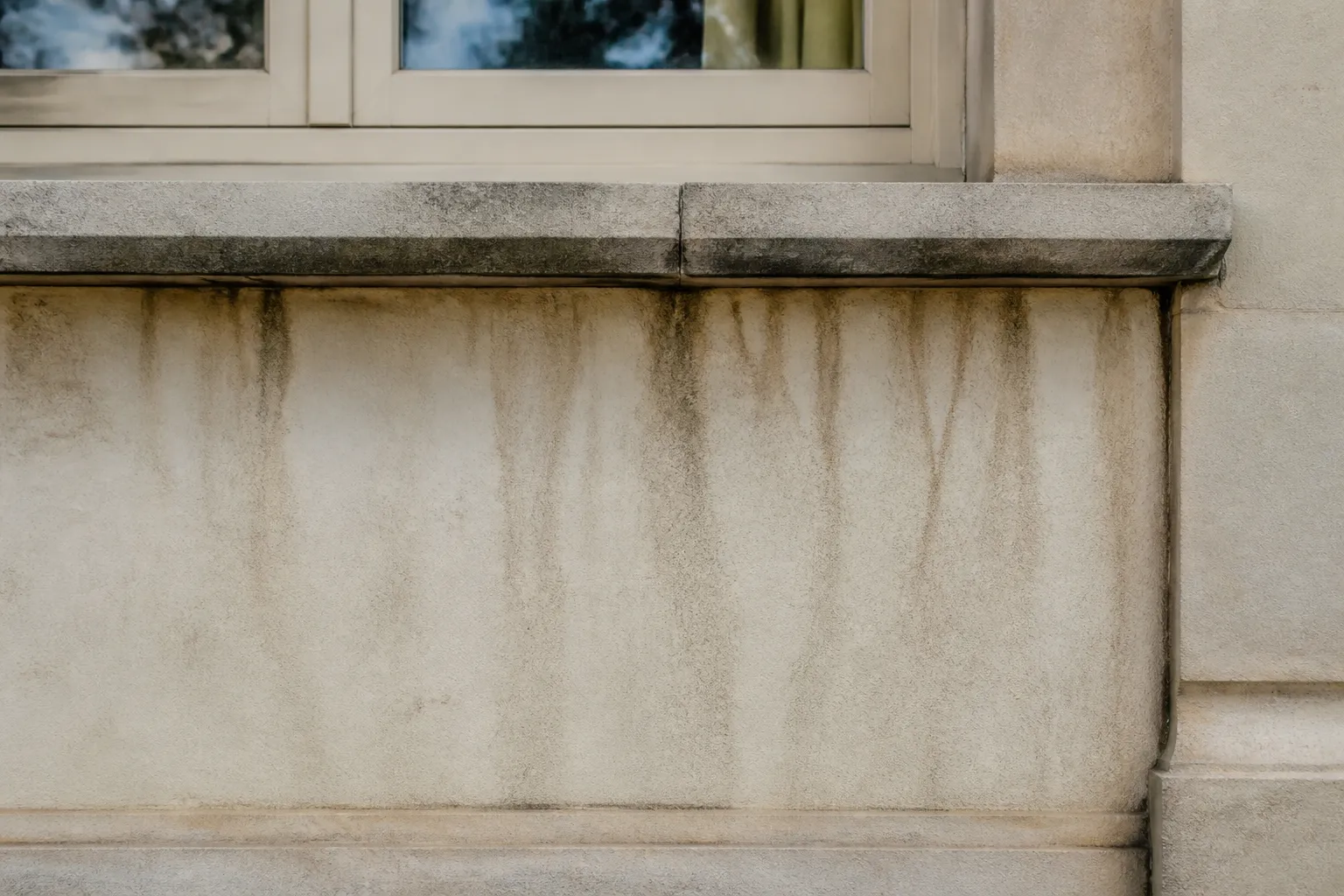 Facade avec traces de ruissellement sous un appui de fenetre